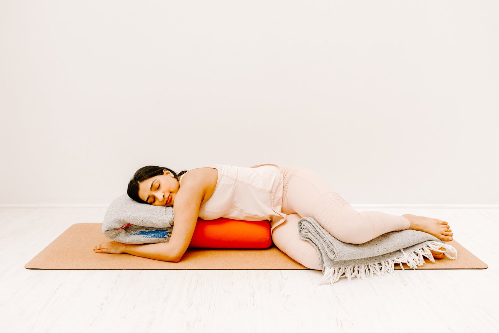 A student resting on her side over a bolster with a blanket beneath her, fully at ease.